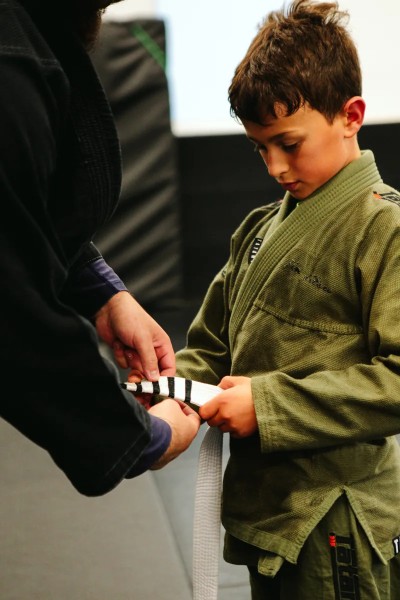 Child receiving a belt promotion at Flow BJJ