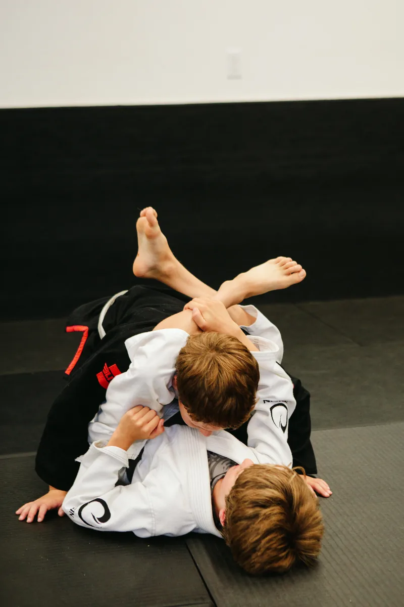 Kids learning Jiu Jitsu technique with a coach