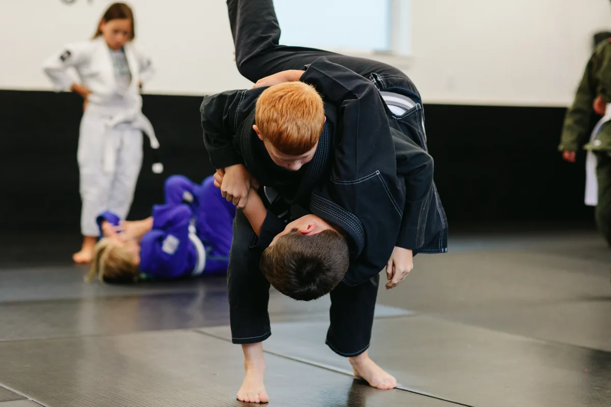 Young student practicing a takedown in kids BJJ class